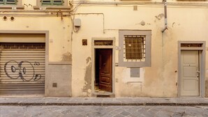 A building with a closed garage door, a wooden door, and a barred window. - Mamo Florence - Aida Apartment (Florence)