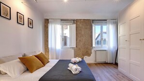 A bedroom with a large bed, two pillows, a rolled towel, and a window with curtains. - Mamo Florence - Aida Apartment (Florence)