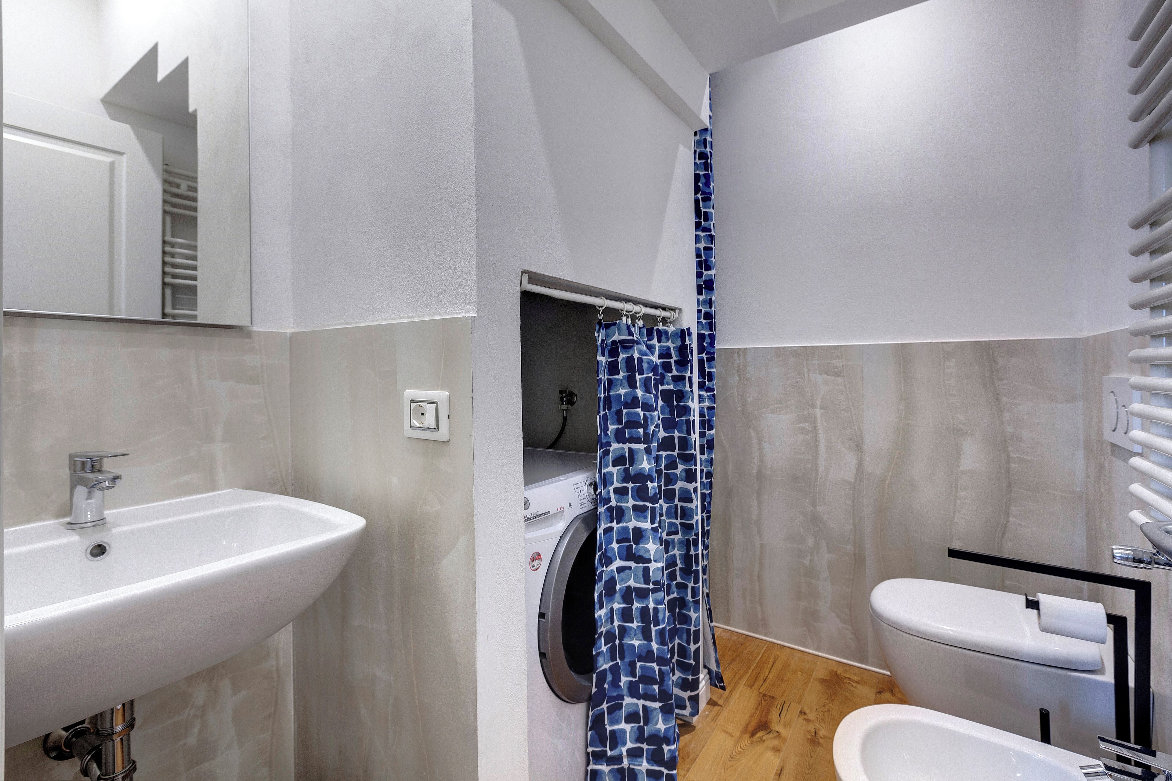 Ein modernes Badezimmer mit Waschbecken, Toilette und Waschmaschine.