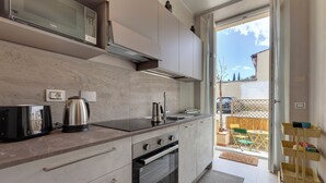 Eine moderne Küche mit integriertem Mikrowellenherd, Backofen und Toaster. Eine Schiebetür führt zu einem Balkon mit Sitzgelegenheit im Freien.