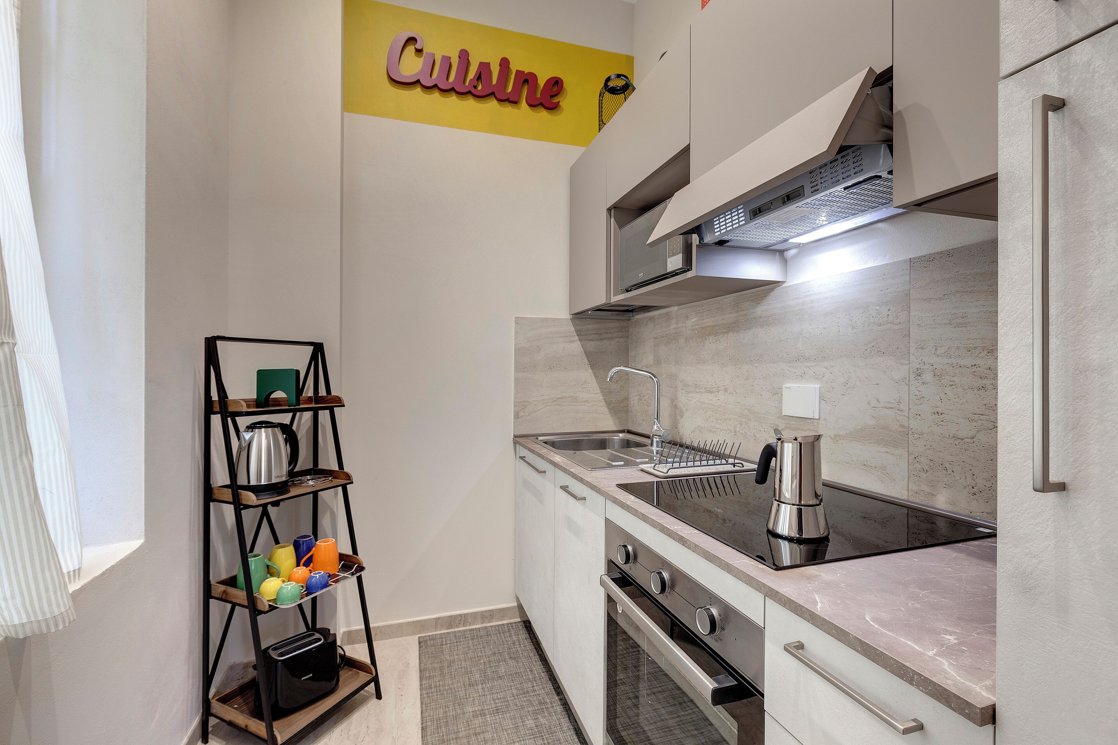 Una cocina moderna con estufa de acero inoxidable, un lavamanos y una cafetera.