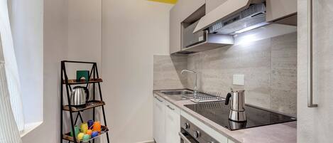 Una cocina moderna con estufa de acero inoxidable, un lavamanos y una cafetera.