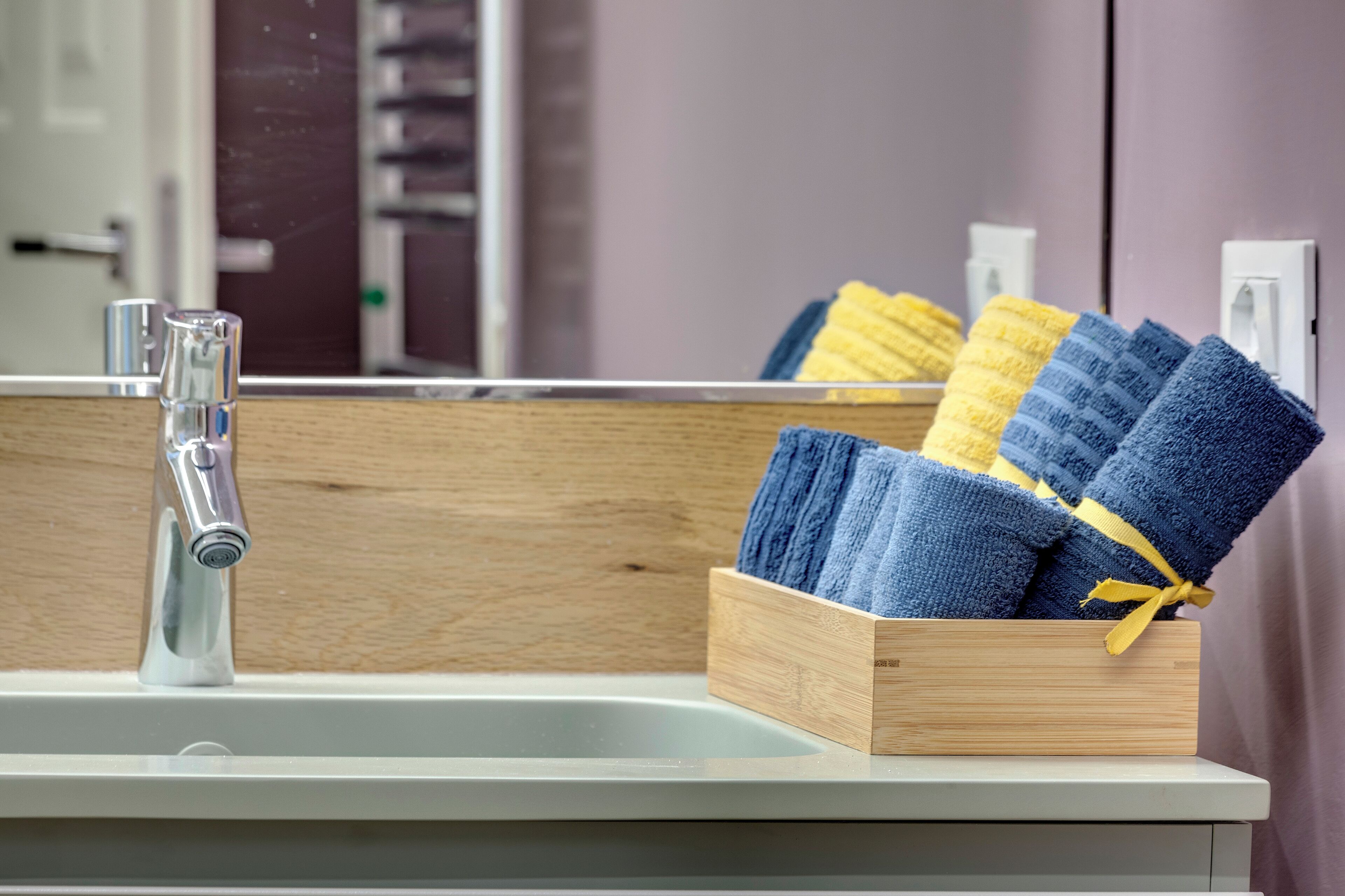 A bathroom sink with a wooden towel rack holding folded towels.
