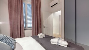 Een hotelkamer met een bed, een raam met zonwering, een kledingkast en een badkamers deur.