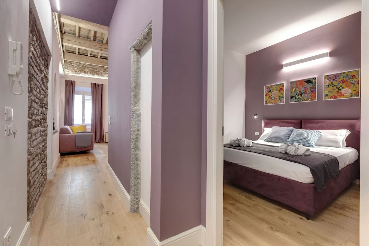 A bedroom with a large bed, purple walls, and a wooden floor.