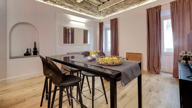 Een moderne eetruimte met een houten plafond, een eettafel met stoelen en uitzicht buiten door grote ramen.