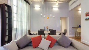A modern living room with a sofa, a dining table, and a bookshelf. - Mamo Florence - Anita Apartment (Florence)
