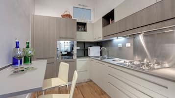 Una cocina moderna con armarios blancos, una estufa de acero inoxidable y un comedor con una silla blanca.