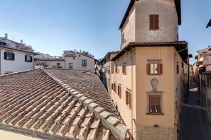 A narrow street with terracotta-tiled roofs and traditional buildings with wooden shutters. - Mamo Florence - Audrey Apartment (Florence)