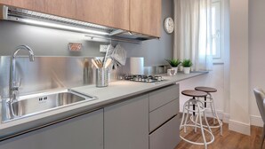 Een moderne keuken met roestvrijstalen apparatuur, houten kastjes en een wit aanrecht.