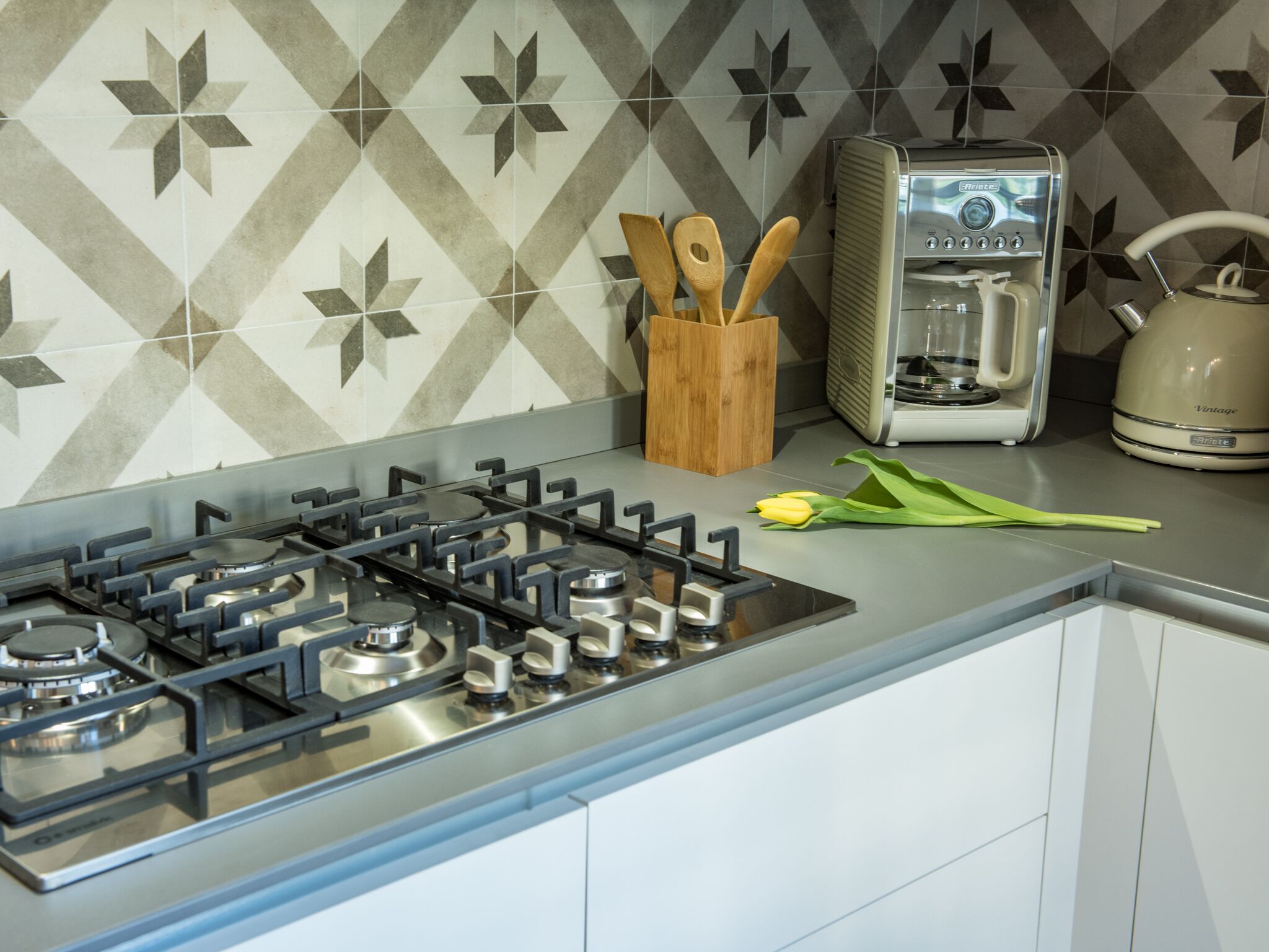 A kitchen with a gas stove, a coffee maker, and a kettle.