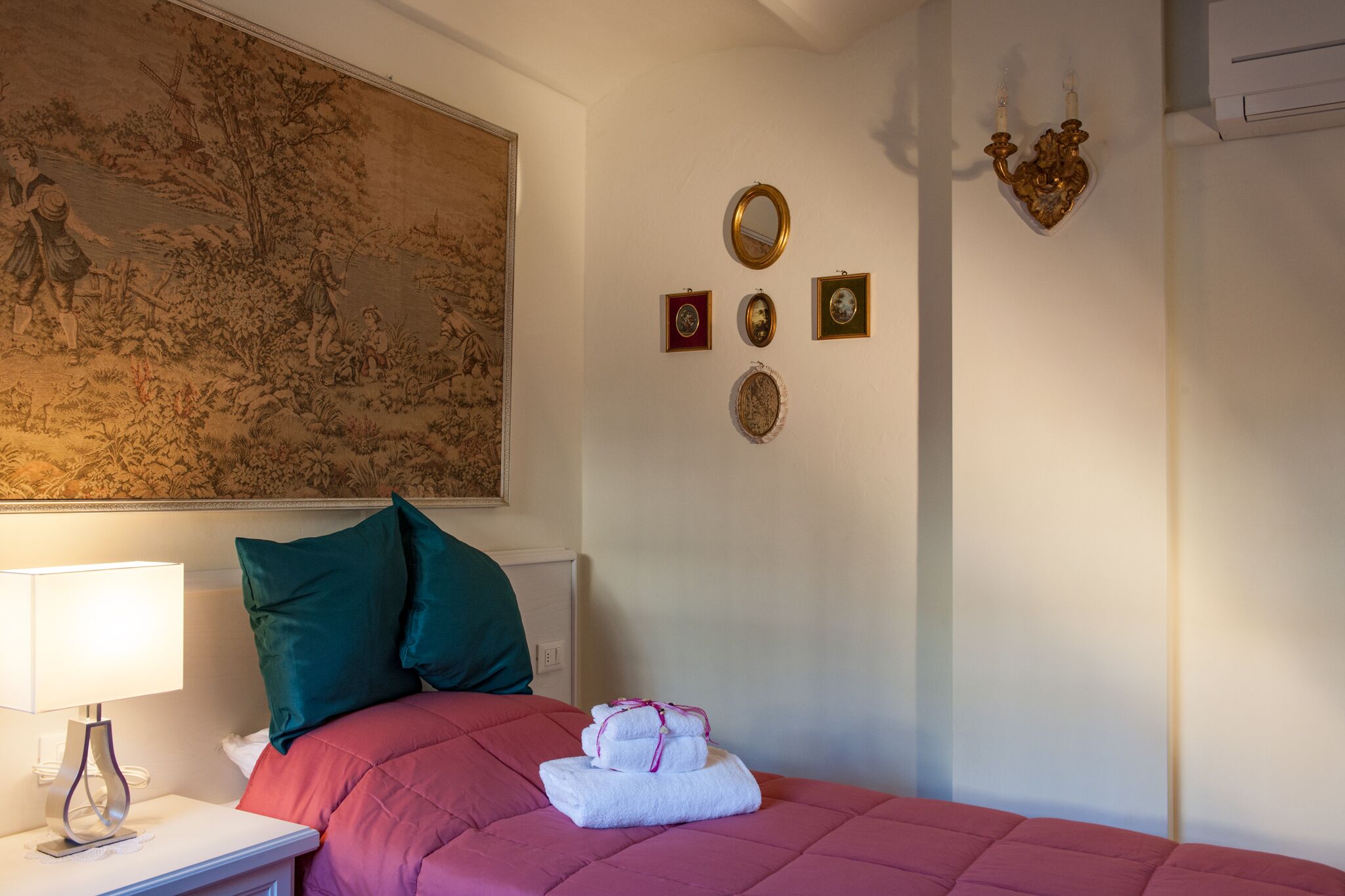 Une chambre d’hôtel comprenant un lit, une table de chevet, une lampe, un mur orné d’un tableau et des éléments de décoration fixés au mur.