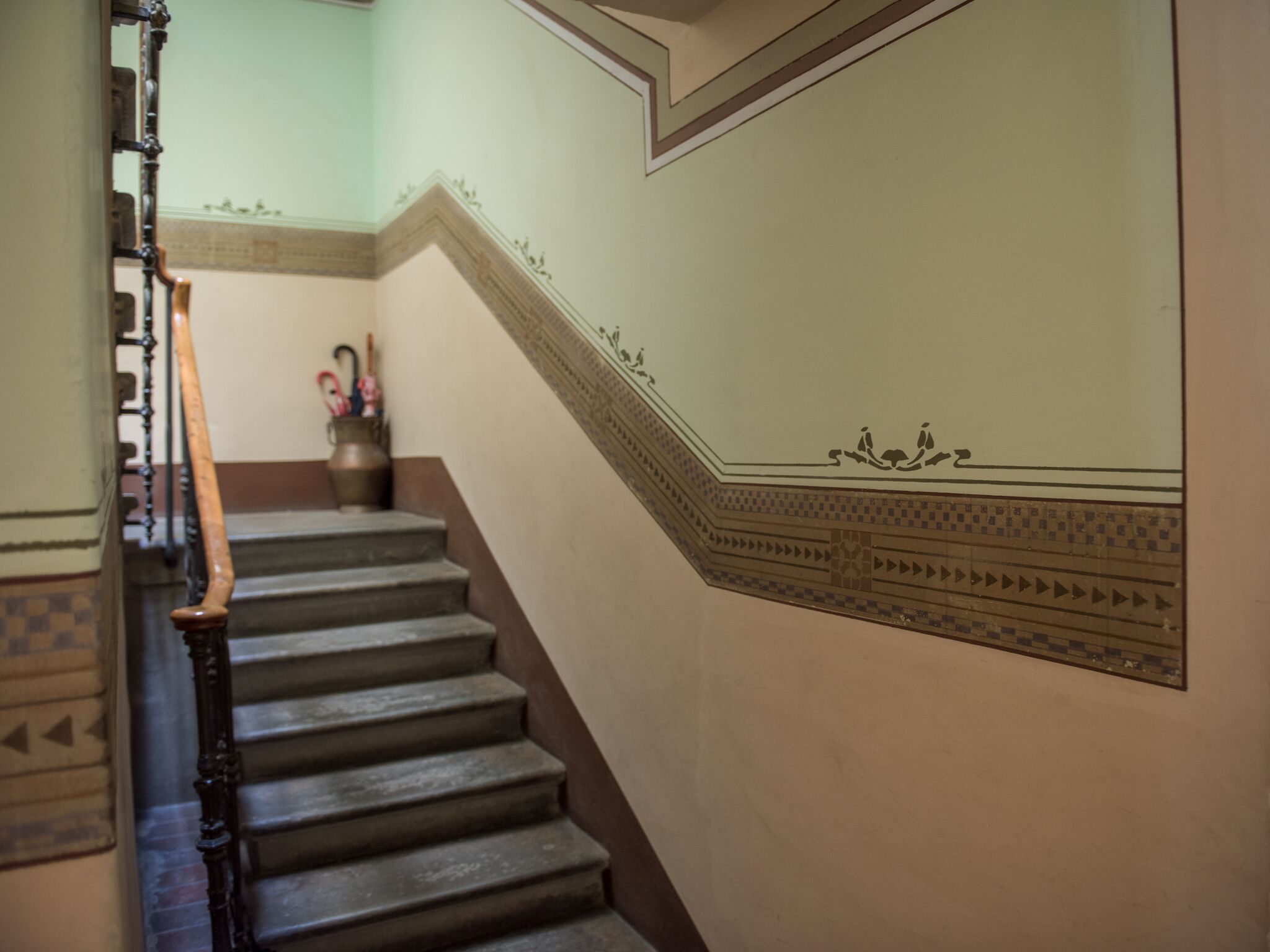 A staircase with a wooden handrail and a decorative wall with geometric patterns.
