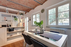 A modern room with a white desk, black chairs, a bookshelf, and a large window with a view of trees. - Mamo Florence - Bonnie - Clyde - Marvin Apartments (Florence)