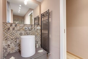 A bathroom with a large white sink, patterned tiles, and a towel rack. - Mamo Florence - Borgo Apartment (Florence)