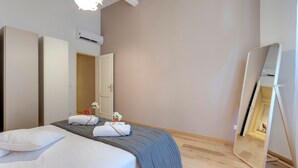Een hotelkamer met een bed, een grote spiegel en een airco aan de muur.