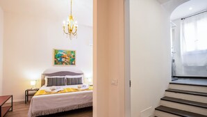 Ένα δωμάτιο ξενοδοχείου με ένα κρεβάτι, ένα πολυέλαιο, έναν πίνακα και μια σκάλα.