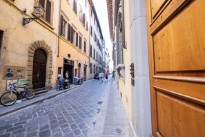 A narrow cobblestone street flanked by historic buildings with wooden doors and shutters. - Mamo Florence - Borgo Santa Croce Apartment (Florence)