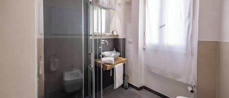 A modern bathroom with a glass-enclosed shower, a wooden vanity, and a white toilet.