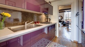 A modern kitchen with stainless steel appliances, a built-in sink, and a vase with yellow flowers. - Mamo Florence - Casper Apartment (Florence)