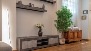 A modern living room with a grey console table, a potted plant, and a wooden cabinet. - Mamo Florence - Cherubini Apartment (Florence)