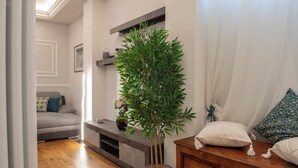 A living room with a sofa, a coffee table, a plant, and a wooden cabinet. - Mamo Florence - Cherubini Apartment (Florence)