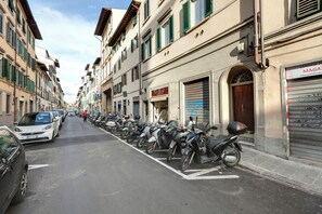 Eine Straße, gesäumt von parkenden Motorrädern und Autos, mit Gebäuden im traditionellen Baustil und Geschäften.
