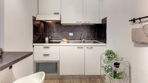 A compact kitchen with white cabinets, a built-in oven, and a small refrigerator. - Mamo Florence - Cristofano Studio (Florence)