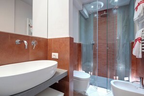 A modern bathroom with a large oval sink, a glass-enclosed shower, and a toilet. - Mamo Florence - Dante & Virgilio Apartments (Florence)