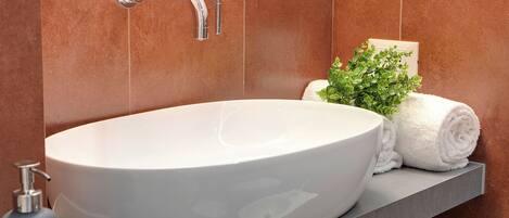 Ein Badezimmer mit einem weißen Aufsatzbecken, einem Handtuch und einer kleinen Pflanze auf der Ablagefläche.