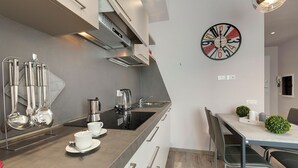A modern kitchen with a built-in stove, a coffee maker, and a clock on the wall. - Mamo Florence - Dante & Virgilio Apartments (Florence)