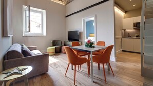 Una sala de estar moderna con un sofá, una mesa de comedor con sillas, un televisor y una zona de cocina.