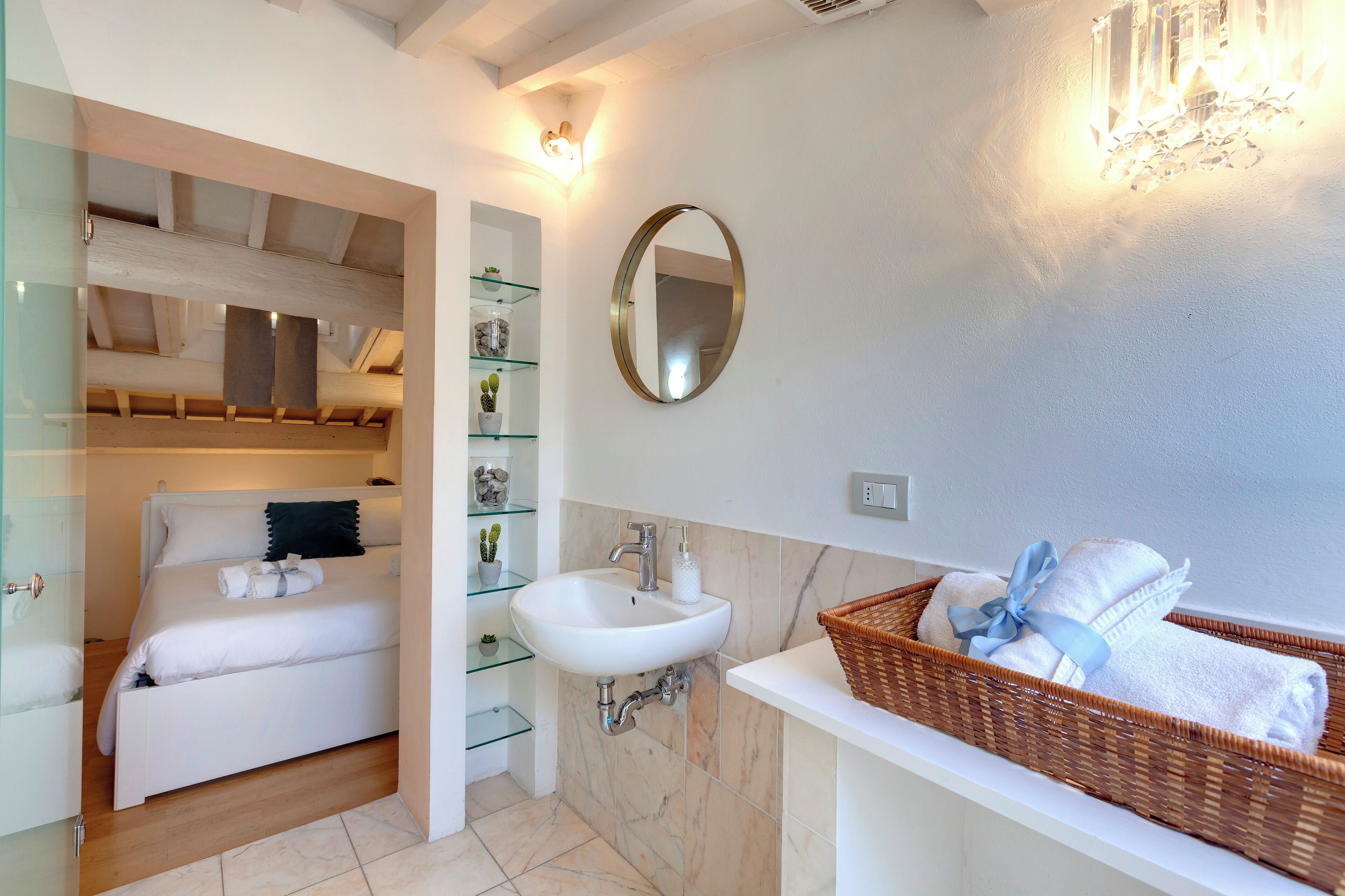 A modern bathroom with a white sink, a mirror, and a wicker basket with towels.