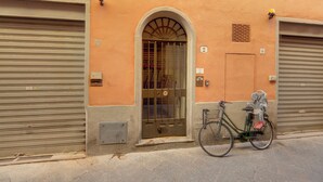 Un edificio con una puerta metálica cerrada, una bicicleta estacionada afuera y un pequeño ventanal con una reja de metal.