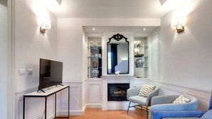 Una sala de estar con televisor, chimenea y un área de descanso con dos sillones y un sofá.
