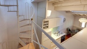 Una cocina con alacenas blancas, una estufa a gas y un comedor con mesa y sillas.