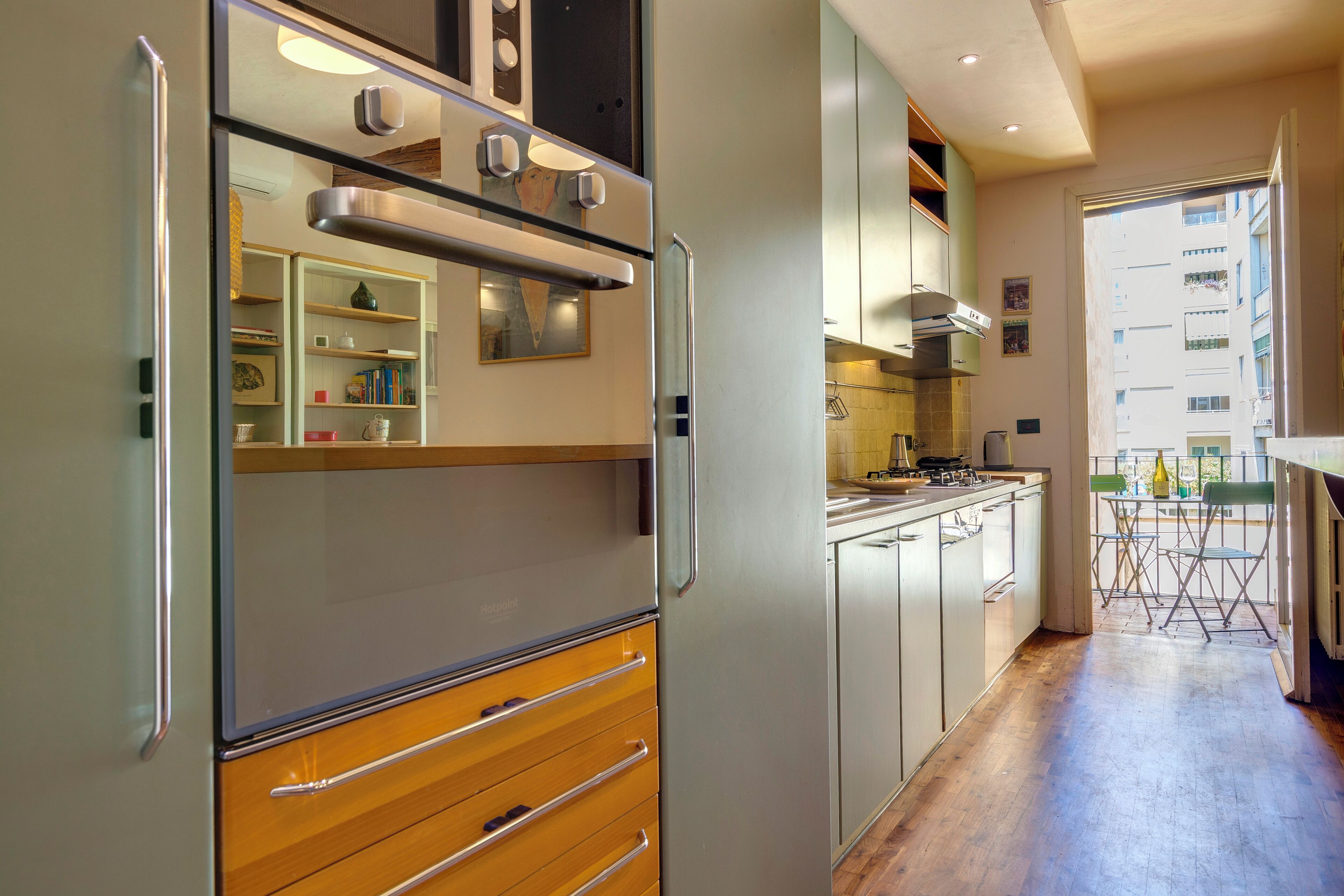A modern kitchen with stainless steel appliances, wooden cabinets, and a dining area with a view of the city.