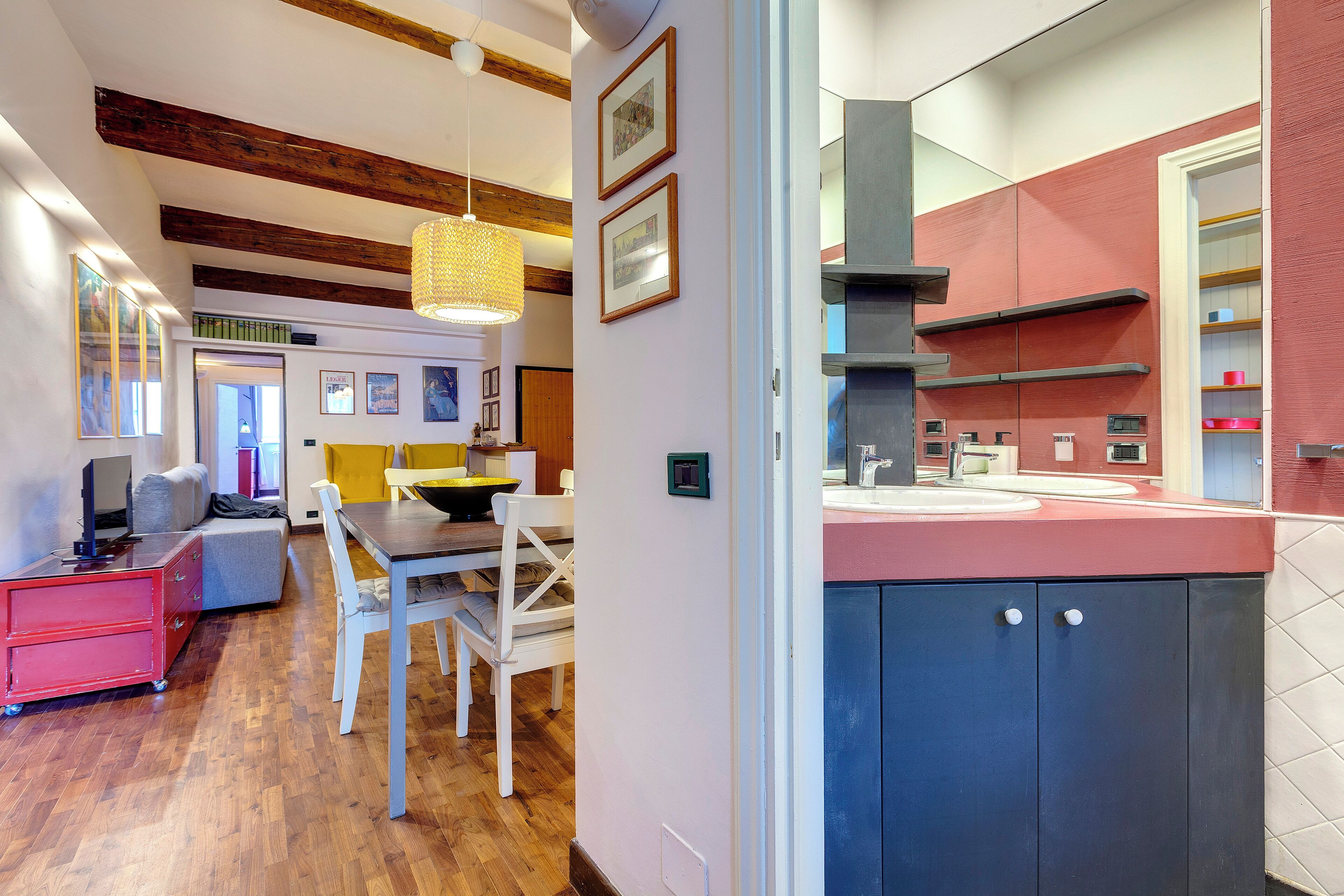 A modern kitchen with wooden beams, a dining area with a table and chairs, and a red storage unit.