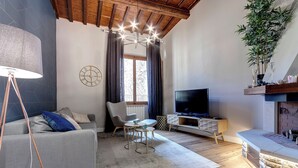 Un soggiorno moderno con un divano grigio, un tavolino, una televisione e un camino.