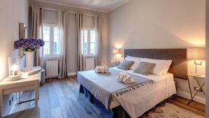 Una camera da letto con un letto, comodini, una lampada, uno specchio e una finestra con tende.