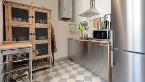 Eine Küche mit einem Edelstahlkühlschrank, einer Mikrowelle und einem Holzkasten mit Glastüren.