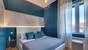 A bedroom with a bed, bedside table, and a window with curtains. - Mamo Florence - Guido Monaco Apartment (Florence)