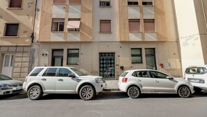 Ein Gebäude mit beige farbenem Mauerwerk, zahlreichen Fenstern und einer mittleren Tür mit Diamantmuster-Verglasung.