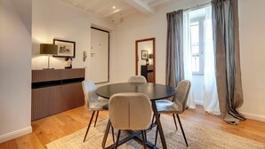 A dining area with a round table, four chairs, a lamp, and a framed picture on the wall. - Mamo Florence - La Badessa Apartment (Florence)