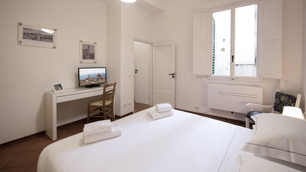 A hotel room with a bed, a desk with a computer, a chair, and a window. - Mamo Florence - Macci Apartment (Florence)