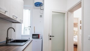 A compact kitchen with a built-in sink, a microwave, and a compact refrigerator. - Mamo Florence - Macci Apartment (Florence)