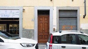 A street view with two parked cars, a wooden door, and a building with a sign reading "La Bottega". - Mamo Florence - Macci Apartment (Florence)