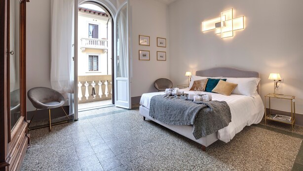 Hotelkamer met een bed, een stoel, een nachtkastje en uitzicht op het balkon.