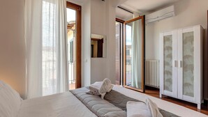 Ein Schlafzimmer mit einem Bett, einem Kleiderschrank und einer Glastür zum Balkon.