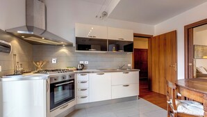 Eine moderne Küche mit weißen Schränken, einem eingebauten Backofen und einer Edelstahl-Dunstabzugshaube.